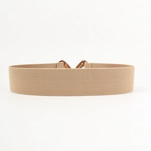 Détail de la ceinture large élastique beige avec une boucle en métal doré poli