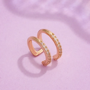 Double-layer rose gold ear cuff with zircons on a soft purple textured background