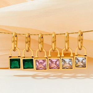 Detailed macro view of gold-plated square lock earrings with emerald and pink crystals