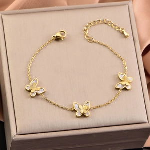 Elegant gold butterfly bracelet with white shell and frosted texture on a jewelry box