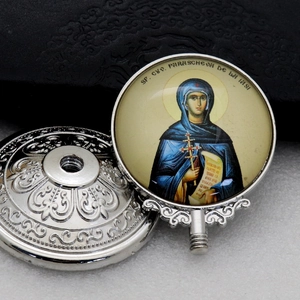 Macro view of silver religious pendant head with saint icon and engraved metal base