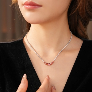 Close-up of minimalist silver necklace featuring a vibrant orange-red gemstone pendant