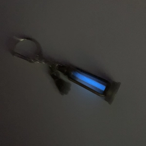 Luminous kerosene lamp pendant glowing in blue light with metallic key ring detail