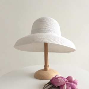 Detailed texture of white woven wide brim straw sun hat on a wooden display stand