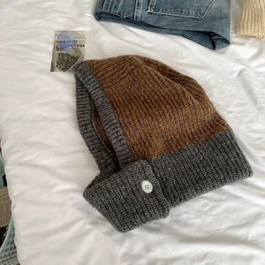 Detail of grey and brown chunky knit Balaclava hood with decorative side buttons