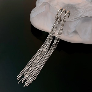 Detail of silver tassel ear cuffs with long bead chains on a frosted display stand