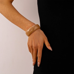 Nahaufnahme des bernsteinfarbenen Acryl-Armreifs mit Marmortextur und hoher Transparenz