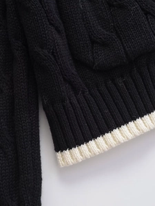 Detailed macro shot of a black cable knit cardigan with white contrast stripes on hem