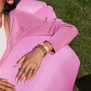 Close-up of stacked gold and silver beaded bracelets and rings on a model's hand
