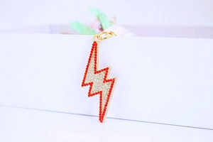 Macro detail of lightning bolt keychain with red and clear rhinestones on gold base