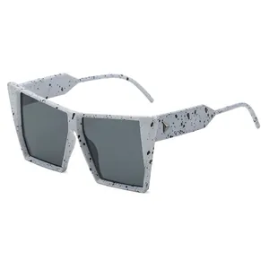 Oversized cat eye sunglasses with ink splatter texture and metal triangle accents