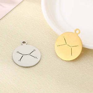 Detail of silver rhinestone and 18K gold zodiac pendants on beige fabric background