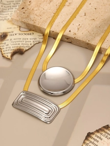 Detail of layered gold snake chains with silver disc and rectangle textured pendants