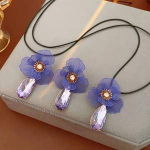 Close-up of purple flower pendants with crystal teardrops on black woven necklaces