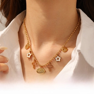 Detail of gold beaded necklace with star moon and sun charms worn on white shirt