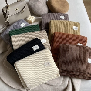 Group shot of ribbed knit winter scarves in various autumn colors with brand labels
