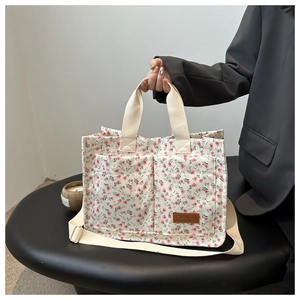 Detail of floral canvas tote bag with front pockets and fashion tag on a table