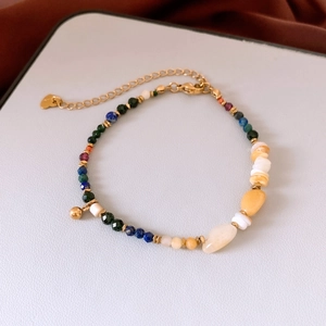 Détail d'un bracelet en perles colorées avec pendentif cœur et chaîne d'extension dorée