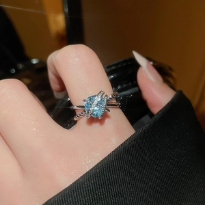 Macro detail of criss-cross silver ring with light blue zircon and pavé setting