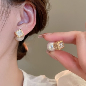 Detail of luxury square zircon earrings with large pearl backing in elegant gold finish