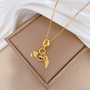 Close-up of golden Hamsa hand, blue evil eye, and feather pendants on a titanium necklace