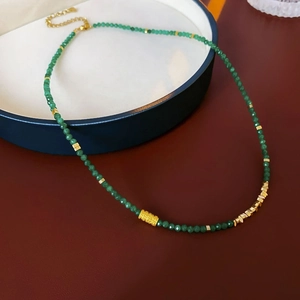 Détail du collier de perles facettées vertes avec intercalaires dorés sur plateau