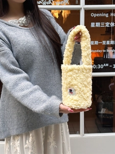 Detail shot of bright yellow faux shearling carry bag with a soft fuzzy texture and strap