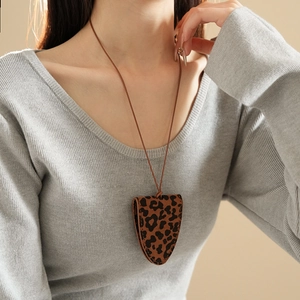 Close-up of leopard print PU leather eyewear pouch necklace worn on a beige sweater