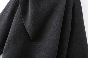 Detailed close-up of dark grey knitted fabric texture with elegant draped folds