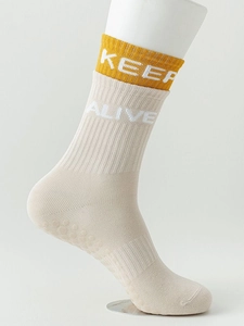 Detail of beige yoga sock with yellow cuff and anti-slip silicone dots on sole