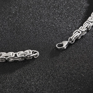 Detailed close-up of a silver stainless steel Byzantine chain with a lobster clasp