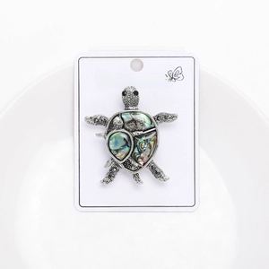 Detail of silver turtle brooch featuring colorful abalone shell inlays and black crystals