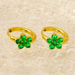 Macro shot of gold floral earrings with green zircon stones and claw setting