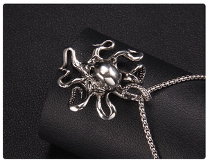 Close-up of silver punk style octopus pendant with skull design on black leather