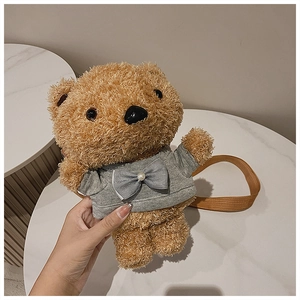 Close-up of brown plush teddy bear bag featuring a gray bow and woven shoulder strap