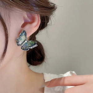 Detail of butterfly earring with blue gradient wings, gold flakes and white pearl bead