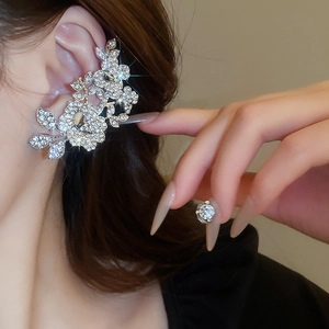Close-up of sparkling rhinestone flower ear cuff and matching stud earring in silver
