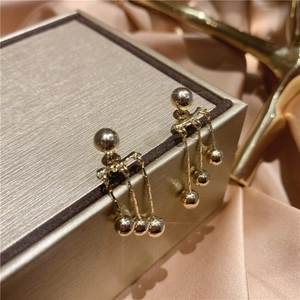 Detail of long gold tassel earrings hanging on a luxury gift box with satin background