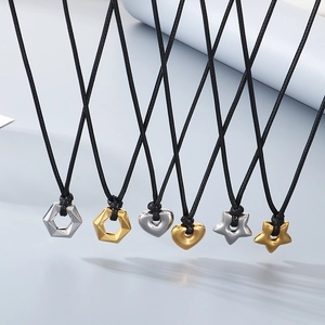 Minimalist gold and silver heart pendant necklaces with black cord on a gray background
