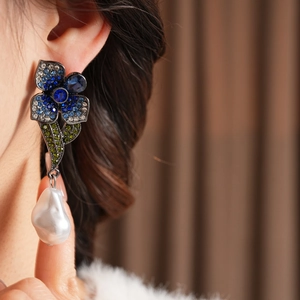 Détail de boucles d'oreilles vintage avec cristaux bleus et perle baroque blanche
