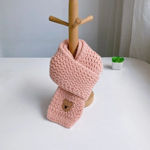Pink knit scarf detail with cute leather bear patch on a wooden hanger display