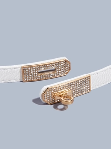 Close-up of white leather belt featuring a gold buckle with sparkling rhinestones