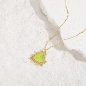 Detail of gold heart pendant with neon green enamel and shimmering zircon stones