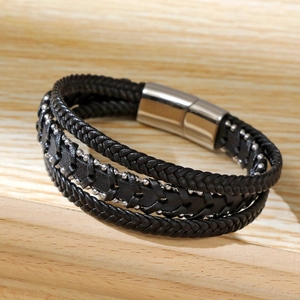 Detail view of black woven microfiber leather bracelet with stainless steel beads on wood