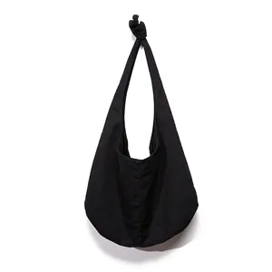 Detail of a black canvas hobo bag with unique knot decoration on the shoulder strap