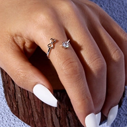 Detail of silver heart ring with single diamond worn on finger with white nails