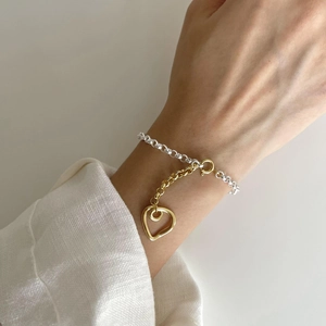 Macro detail of S925 sterling silver heart bracelet with two-tone gold and silver finish