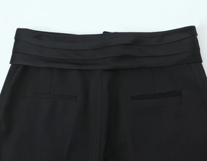Détail d'un pantalon noir habillé avec une taille haute plissée en satin élégante