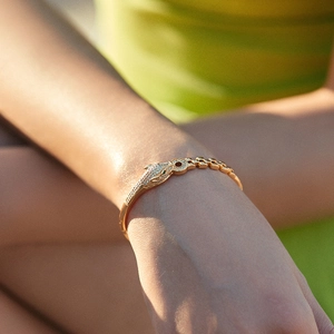 Macro detail of 18K gold plated leopard head bracelet with green gemstone eyes and pavé stones