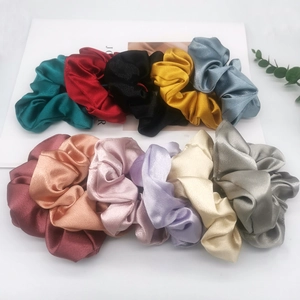 Flat lay of satin hair scrunchies in 11 colors including green, red, black, and gold